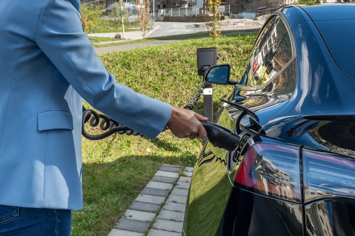 Client satisfait branchant son véhicule électrique grâce à l'aide borne de recharge Smart Electro