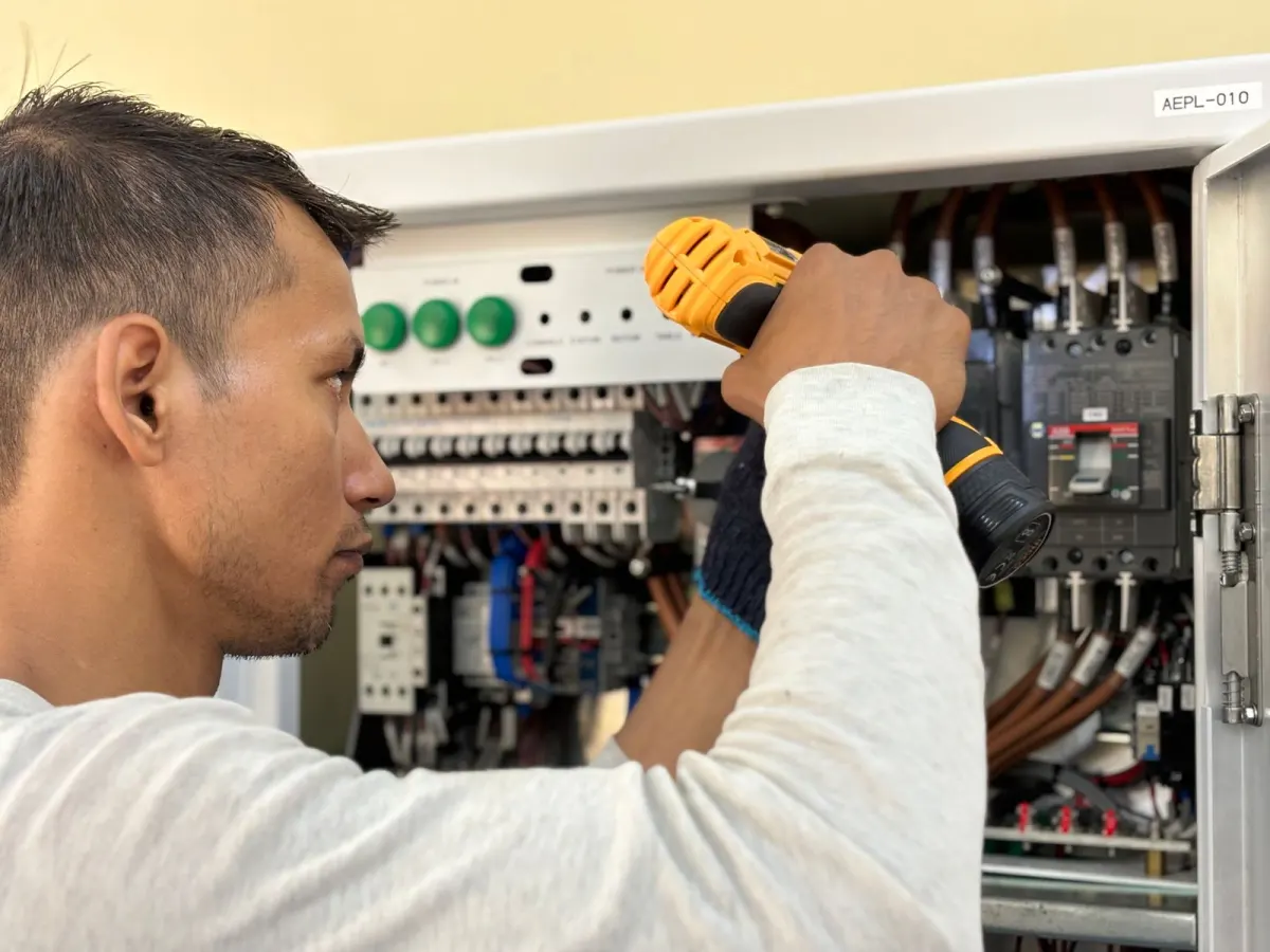 Technicien réglant le panneau électrique d'un bâtiment tertiaire dans le cadre du décret tertiaire