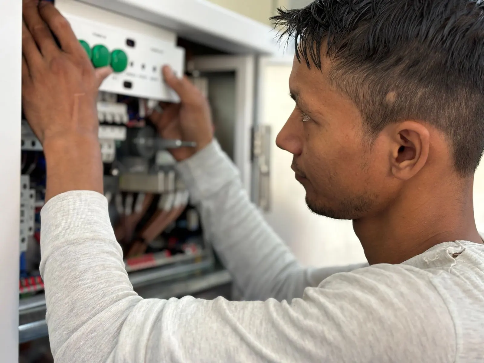 Technicien raccordant un interrupteur différentiel dans un tableau électrique conforme à la norme NF C 15-100